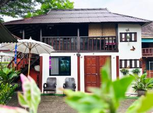 a house with an umbrella and two chairs in front of it at Thai Tom s GuestHouse in Chiang Mai +115 photos