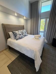 a bedroom with a bed with pillows and a window at Haven Luxury Apartment in Windhoek