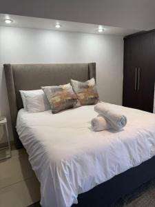 a large bed with white sheets and pillows at Haven Luxury Apartment in Windhoek