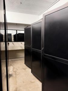 un baño con dos cabinas negras en una habitación en J Walker Hostel, en Weligama 8 fotos más