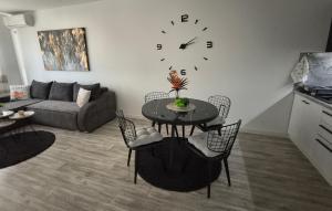 a living room with a table and a clock on the wall at PANORAMA Apartment Sombor in Sombor