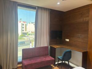 a room with a chair and a desk and a window at Hotel Maria in Dera Bassi