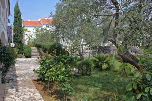a garden with trees and bushes and a house at Apartment Porat 5322c in Malinska