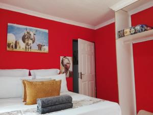 a bedroom with red walls and a bed at Encome Guest House in Pongola
