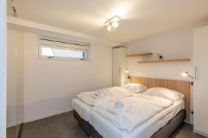 Un dormitorio con una cama con sábanas blancas y una ventana. en Zonnedorp 26 Renesse: Comfortabele Strandvakantie aan de Noordzee, en Renesse