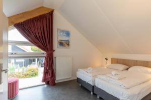 Un dormitorio con dos camas y una ventana. en Zonnedorp 26 Renesse: Comfortabele Strandvakantie aan de Noordzee, en Renesse