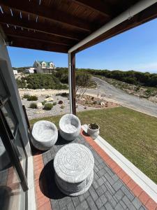 een terras met drie stenen zitplaatsen op een veranda bij Seebossie in Struisbaai