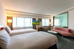 a hotel room with two beds and a couch at United Hotel in Taipei