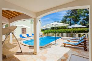 einen Pool mit Stühlen und Sonnenschirmen auf einer Terrasse in der Unterkunft Seaside family friendly house with a swimming pool Brna - Vinacac, Korcula - 9266 in Prizba