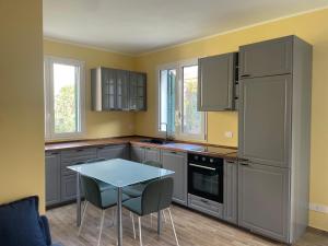 a kitchen with gray cabinets and a table with chairs at PALAZZO RICARDI Chambres d'hotes in Imperia