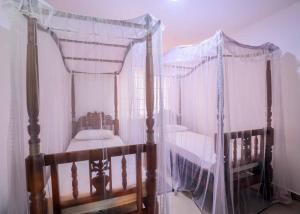a bedroom with a four poster bed with a canopy at Gin Villa in Kammala South