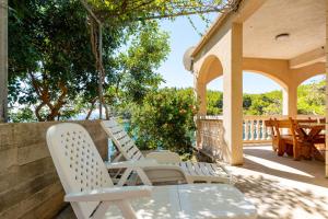 two white chairs and a table on a patio at Apartments by the sea Cove Zaglav, Korcula - 12208 in Prizba