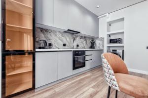 Отличный вариант рядом с Новым вокзалом في أستانا: مطبخ مع خزائن بيضاء وكرسي