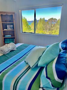 a bedroom with a bed with a large window at Bush & Bay Hideaway in Cable Bay