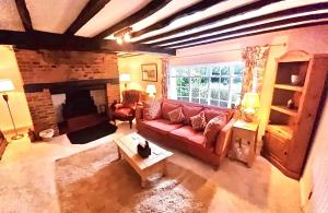 a living room with a red couch and a fireplace at Charming 3 bed kent Cottage in Chilham