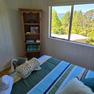 a bedroom with a bed with a large window at Bush & Bay Hideaway in Cable Bay