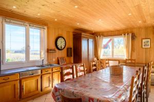 eine Küche mit einem Tisch und einer Uhr an der Wand in der Unterkunft Gîte À L'ancienne Boulangerie in Elsenheim