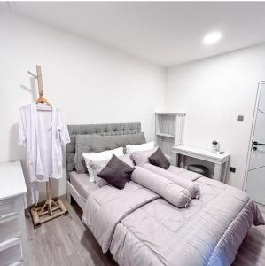 a white bedroom with a large bed with pillows at Atropa belladonna in Sembalun Lawang