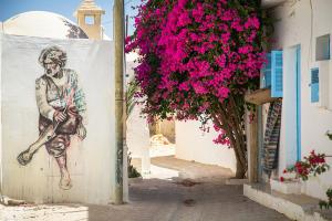 a mural of a man on a wall with pink flowers at trip to djerba in Djerba