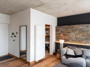 a living room with a white couch and a stone wall at N8Quartier Eifel in Bad Münstereifel