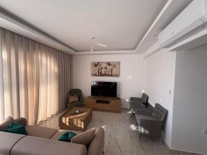 Una sala de estar con un sofá y un televisor. en Poseidon North Ciprus, Tatlisu, 