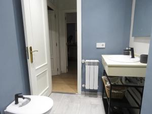 une salle de bains avec deux lavabos et une porte donnant sur un couloir dans l'établissement La Casina Poniente,cerca de la playa, à Gijón