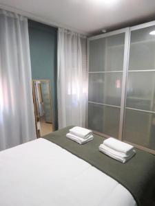 une chambre avec un grand lit blanc avec deux serviettes pliées dans l'établissement La Casina Poniente,cerca de la playa, à Gijón