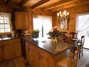 eine Küche mit einem Tisch mit einer Vase mit Blumen darauf in der Unterkunft Family Cabin Vacation Getaway with Waterfall Views in Northwest Arkansas in Ponca