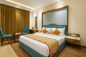 アムリトサルにあるHotel Amrit viewのベッドルーム(大型ベッド1台、青い椅子付)