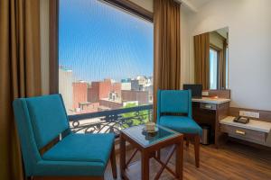 アムリトサルにあるHotel Amrit viewの椅子2脚、デスク、大きな窓が備わる客室です。