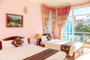 two beds in a room with a window at Orient Tam Đảo Hotel in Tam Ðảo