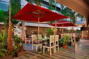 a patio with tables and chairs and red umbrellas at Afallon Hotels in Bangalore