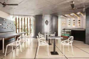 a dining room with white chairs and tables and windows at Afallon Hotels in Bangalore