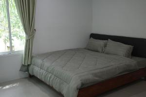 Una cama en una habitación blanca con ventana. en Palm tree garden house NinemintoAonangbeach, en Ao Nam Mao