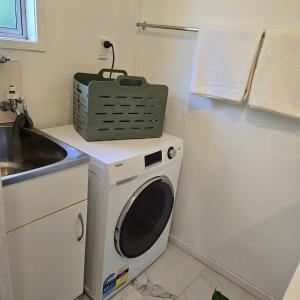a washing machine with a green basket on top of it at Bush & Bay Hideaway in Cable Bay