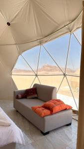 a couch in a tent with a view of the desert at MARS MIRROR BUBBLE lUXURY CAMP in Wadi Rum