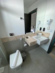 a bathroom with a sink and a toilet and a mirror at Uberlândia Suítes Hotel in Uberlândia +57 photos