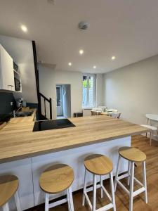 a kitchen with a counter with three stools and a counter top at Maison Entre Verre et Mer in Eu