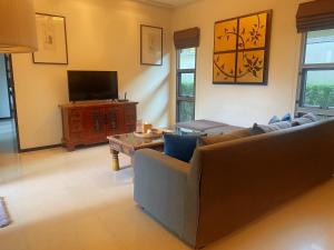 ein Wohnzimmer mit Sofa und Fernseher in der Unterkunft The Niche10 - Oriental Villa 3BR private pool Rawai Beach in Nai Harn Beach