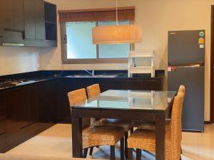 eine Küche mit einem Glastisch mit Stühlen und einem Kühlschrank in der Unterkunft The Niche10 - Oriental Villa 3BR private pool Rawai Beach in Nai Harn Beach