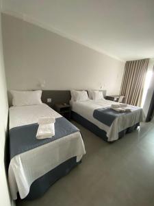 a hotel room with two beds and a window at Uberlândia Suítes Hotel in Uberlândia