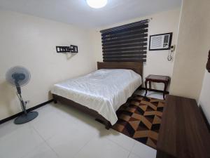 a bedroom with a bed and a desk and a fan at David home in Manila