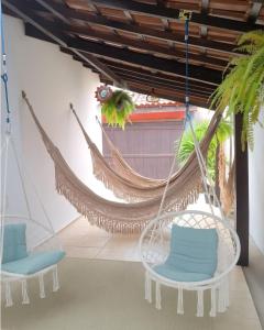 a hammock in a room with two chairs at Pousada Lira Praieira Paraty in Paraty