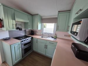 a kitchen with green cabinets and a stove and a sink at Lodge Priscilla in Eext