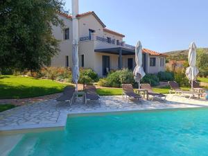 DhorizátaにあるAetheria Villa Kefaloniaのスイミングプール(椅子、パラソル付)が備わるヴィラです。