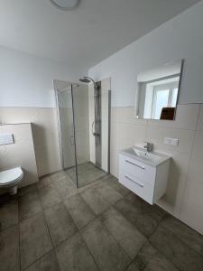 a white bathroom with a shower and a sink at Stadtquartier Völkermarkt in Völkermarkt