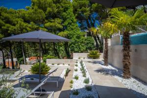 a patio with an umbrella and chairs and a pool at Apartments with swimming pool Brela, Makarska - 19345 in Brela