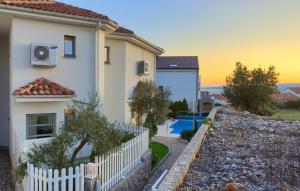 a white house with a fence and a pool at Holiday house with a swimming pool Krk - 23581 in Krk