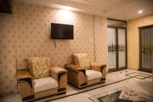 a living room with two chairs and a flat screen tv at Hotel Atithi Inn in Gwalior