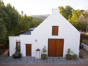 a white barn with wooden doors and trees at Adderley House Guest Accommodation in Robertson +13 photos
